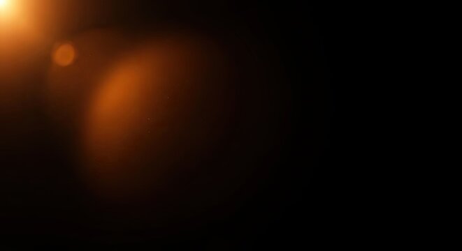 Abstract Warm Orange Lens Flare Overlay on Black Background.