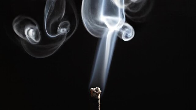 A thin trail of white incense smoke curling elegantly into complex patterns against a dark background.
