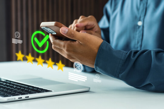 Businessman using a mobile phone giving a five-star verified rating. Concept of customer satisfaction, five star rating on mobile, representing customer feedback, satisfaction review, digital feedback