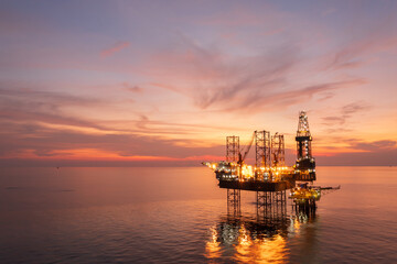 Fototapeta premium Aerial view of offshore jack up rig in a shipyard during sunset for oil and gas exploration and production.