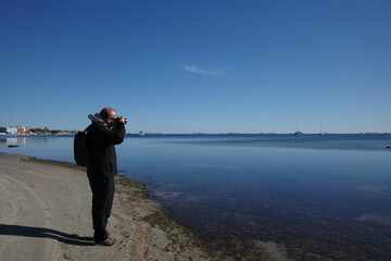 Fototapeta premium Man photographing the Mar Menor on a sunny winter day