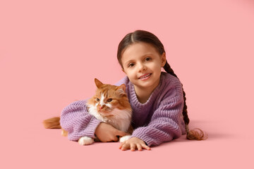 Cute little girl with fluffy cat lying on pink background