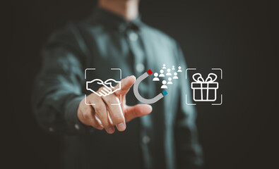 Businessman interacting with digital icons of handshake, magnet attracting people, and gift box illustrating customer engagement and loyalty
