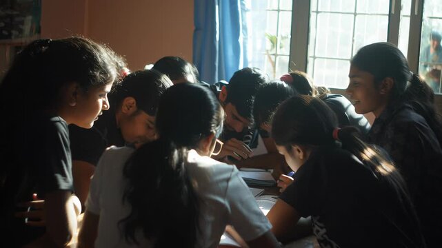 Group of Indian students gathered around a table, one student explaining while others listen attentively, shared ownership of learning, natural classroom light