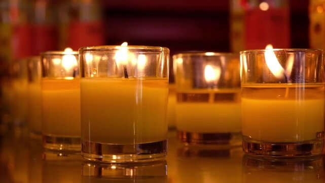 Row of lit votive candles in glass holders creating a warm and peaceful ambiance
