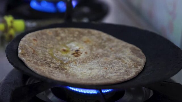 Cooking a healthy chapati made from Uttarakhand mota anaj coarse grains on a gas stove, featuring nutrient-dense millets like jowar, bajra, and ragi, showing traditional cooking, healthy diet.