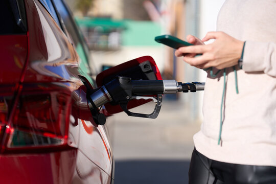 Woman refueling car with compressed natural gas using smartphone