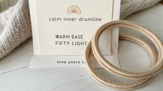 Neutral Natural Tones with Wooden Bracelets on a Light Background Featuring a Calm Inner Drumline Display Card