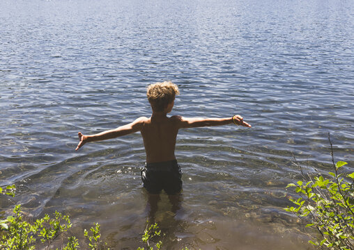 boy holding hands out in a lake
