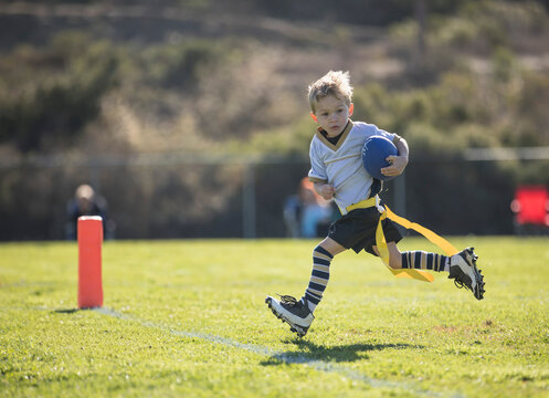 young boy about to score a touchdown in flag football