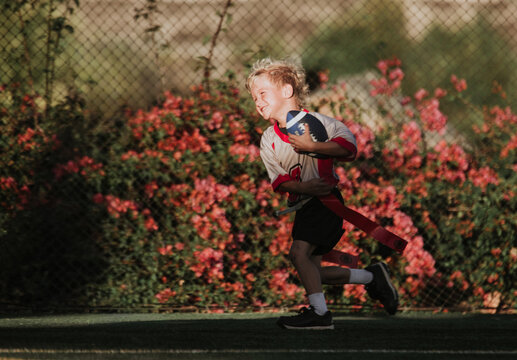 boy running with a football in flag football