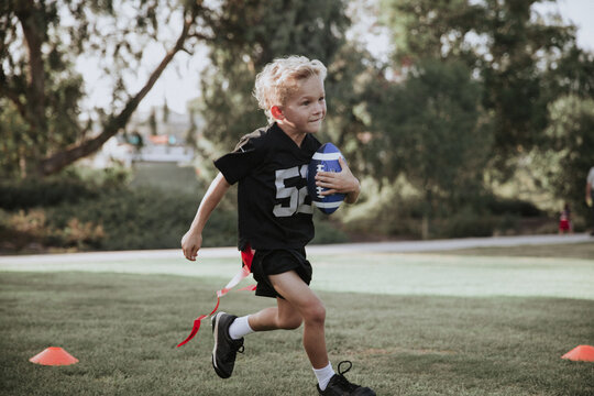 boy running with a football in flag football