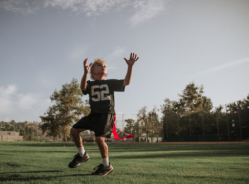 boy reaching up to catch a ball