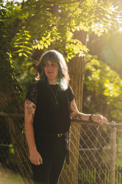 Transwoman leaning on a chainlink fence