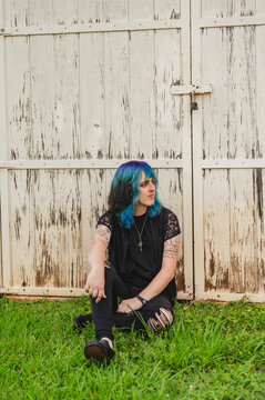 Transwoman leaning on a wall in the grass