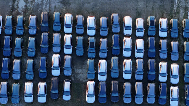 Rows of new cars parked in a large outdoor distribution lot