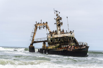 Fototapeta premium The rusted Zeila shipwreck rests along the remote Atlantic coastline of Namibia’s Skeleton Coast. Once a fishing vessel, the abandoned ship now stands as a powerful symbol of the ocean’s strength.