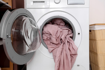 Washing machine with pink bed sheets in laundry room