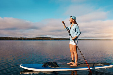 River, happy and woman on surfboard, paddle and adventure on vacation, space and training in...