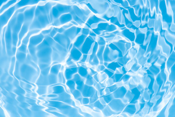 Obraz premium Blue water with ripples on the surface. Defocus blurred transparent blue colored clear calm water surface texture with splashes and bubbles. Water waves with shining pattern texture background.
