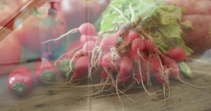 Showing bunch of red radishes twine binding roots lying on rustic tabletop with glass reflection
