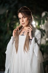 Mysterious woman with tattoos and piercings in a white lace dress, looking at the camera