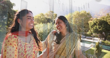 Laughing mother and daughter standing on home balcony, in kurta and saree with candlestick overlay