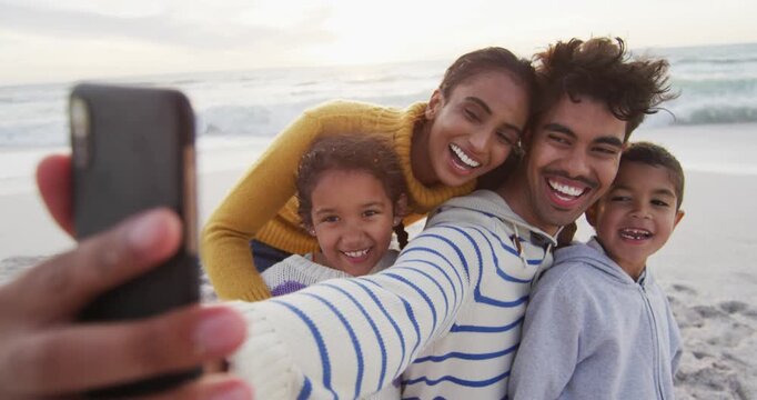 Happy hispanic family taking selfie on beach
