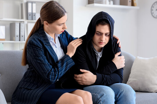 Female psychologist hugging drug addict on sofa in office