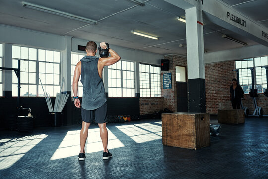 Gym, back and man with kettlebell for bodybuilding, exercise and strong arm muscle development. Weightlifting, workout and male body builder with sweat, fitness or power training at sports club