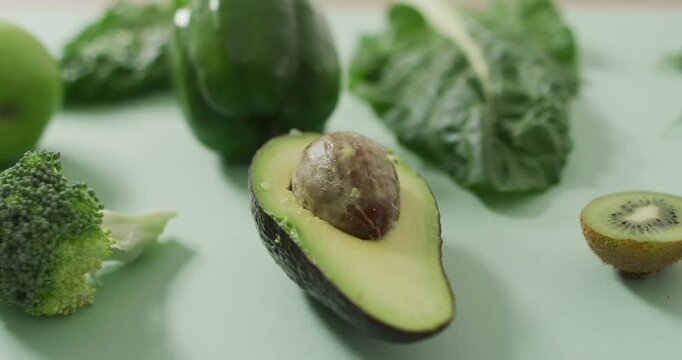 Video of fresh avocado, broccoli, green pepper and green leaves on green background