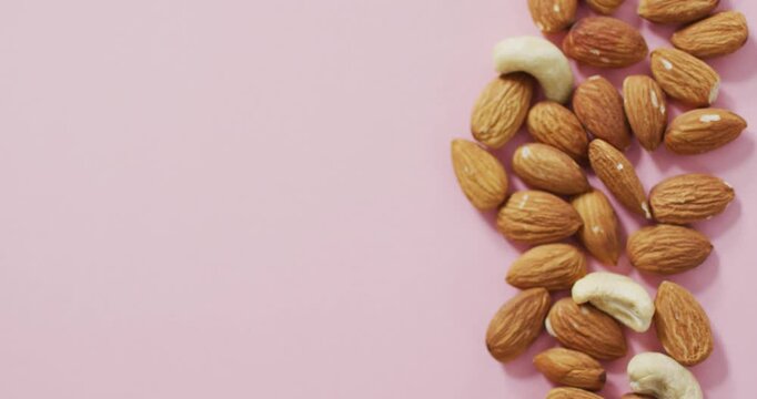 Video of almonds and nuts on pink background