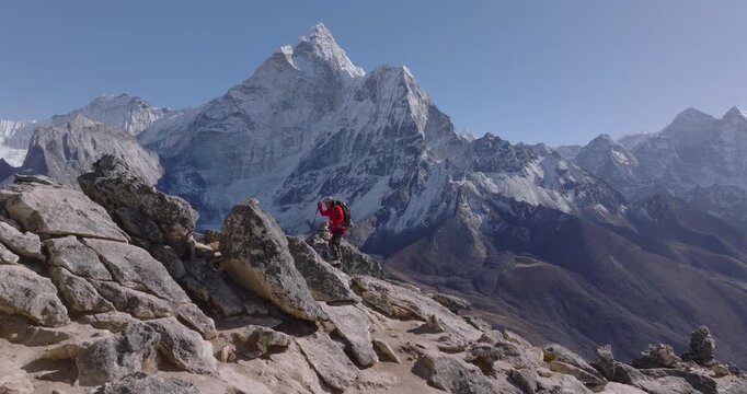 A male tourist hikes toward the summit of Nangkartshang Peak at Dingboche, enjoying sweeping Himalayan views with Ama Dablam and the Khumbu mountain ranges in Nepal&rsquo;s Everest region.