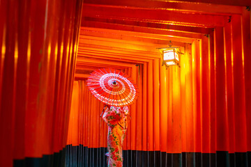 Girl wearing a traditional Japanese kimono at Torii gates in Kyoto, Japan