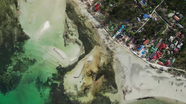Wide aerial seascape featuring a tropical island with palm trees, white sand, and crystal clear water.