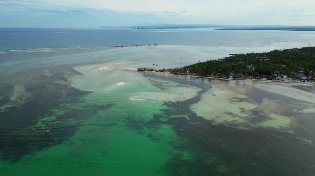 Aerial showing gently curved white sand shoreline with tropical palm trees and crystal clear water at Tondol Beach.