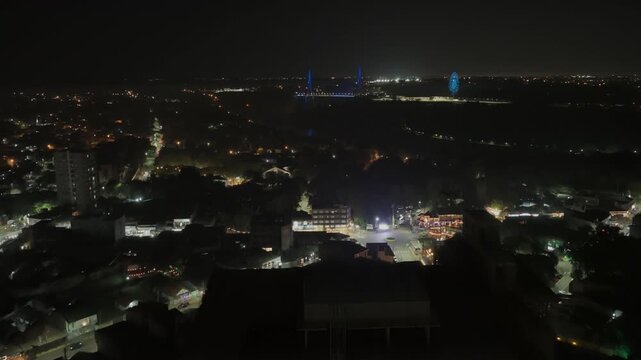 Aerial dolly in over tall building in Puerto Iguazu, showing Integration Bridge lit in blue and city lights across tri-border area between Argentina, Brazil and Paraguay
