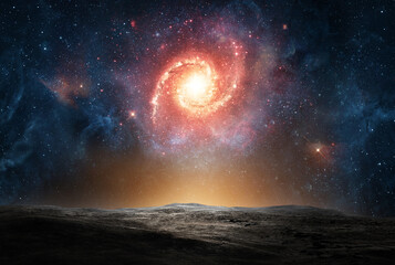 Bright spiral galaxy glowing in deep space above a dark alien surface. Cosmic scene showing stars, light, and the vast universe beyond a distant horizon. Elements of this image furnished by NASA.