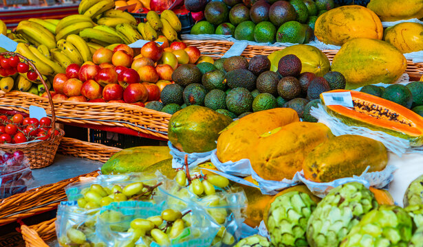 Vibrant fruit display with papaya and avocados at Funchal market.