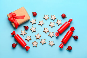 Star-shaped gingerbread cookies with candies, Christmas balls and gift box on blue background
