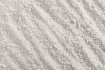 A close-up macro photo of vitamin A powder, showing a soft, granular texture and a creamy white color. The image depicts subtle ridges and fine linear structures on the surface of the powder.