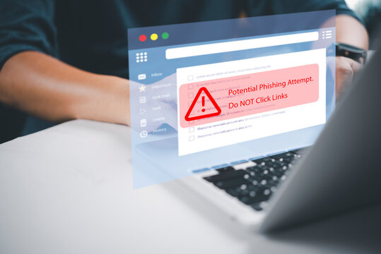 Businessman using laptop with potential phishing attempt warning pop-up on email interface. Concept of cyber crime, email scam, and malicious link danger.