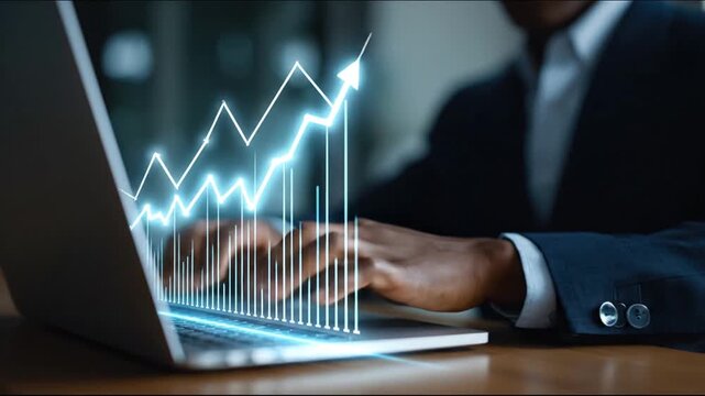 A person in a suit works on a laptop, with a glowing line graph visualizing rising financial data