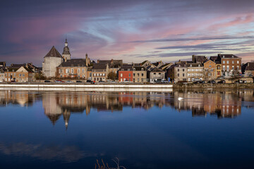 La ville de Givet au coucher du soleil, sur les quais de la Meuse avec le Fort de Charlemont, la tour Victoire et les habitations au bord de l'eau. © Cristian