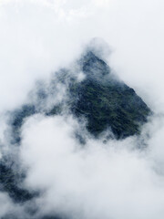 Carrauntoohil mountain peak appears through a blanket of thick, white clouds. The dark, rugged terrain is partially visible, creating an atmospheric and mysterious natural landscape in Ireland.