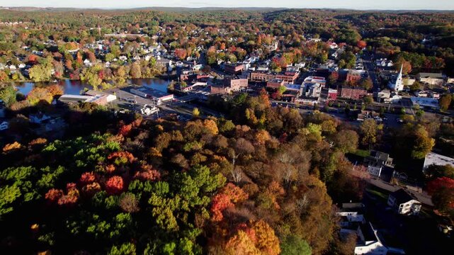 Aerial drone shot over fall foliage trees on the outskirt of a scenic new england downtown in Hudson, Massachusetts.