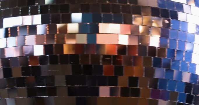 mirror ball spins and lights up with colorful lights for a disco in a dance hall.