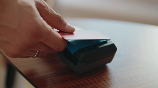 Close-up of a hand holding a credit card and tapping it on a POS terminal to make a secure and fast contactless payment, symbolizing modern financial transactions and consumer convenience