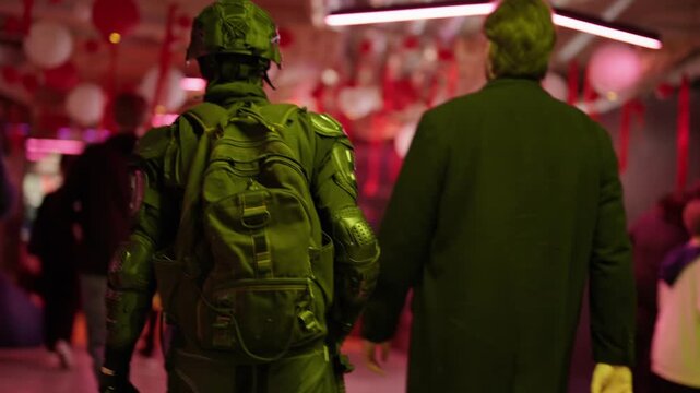 Rear view of a person in full tactical gear walking through a crowded street at night under neon lights, suggesting a cyberpunk or dystopian future with advanced military or police presence