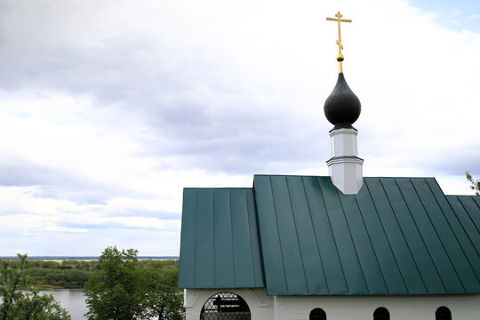 Golden orthodox cross on black dome and green roof top of Spaso-Preobrazhensky Monastery